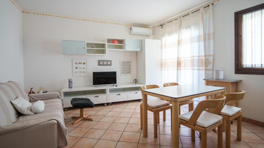 een woonkamer met een tafel en een televisie bij Welcomely - Sunny House in Olbia