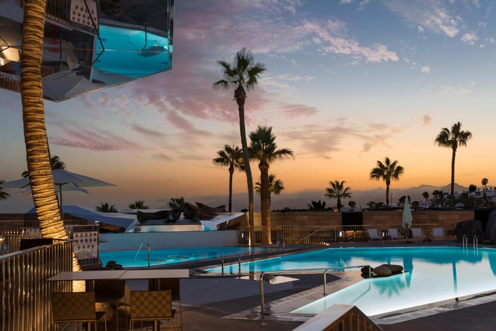 a pool at a resort with palm trees at La Isla y el Mar, Hotel Boutique in Puerto del Carmen