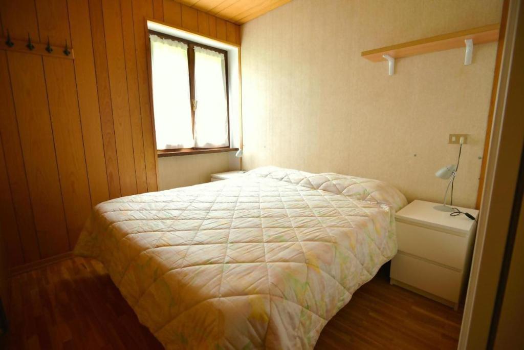 mała sypialnia z łóżkiem i oknem w obiekcie Casa Faè Dolomiti w Madonna di Campiglio