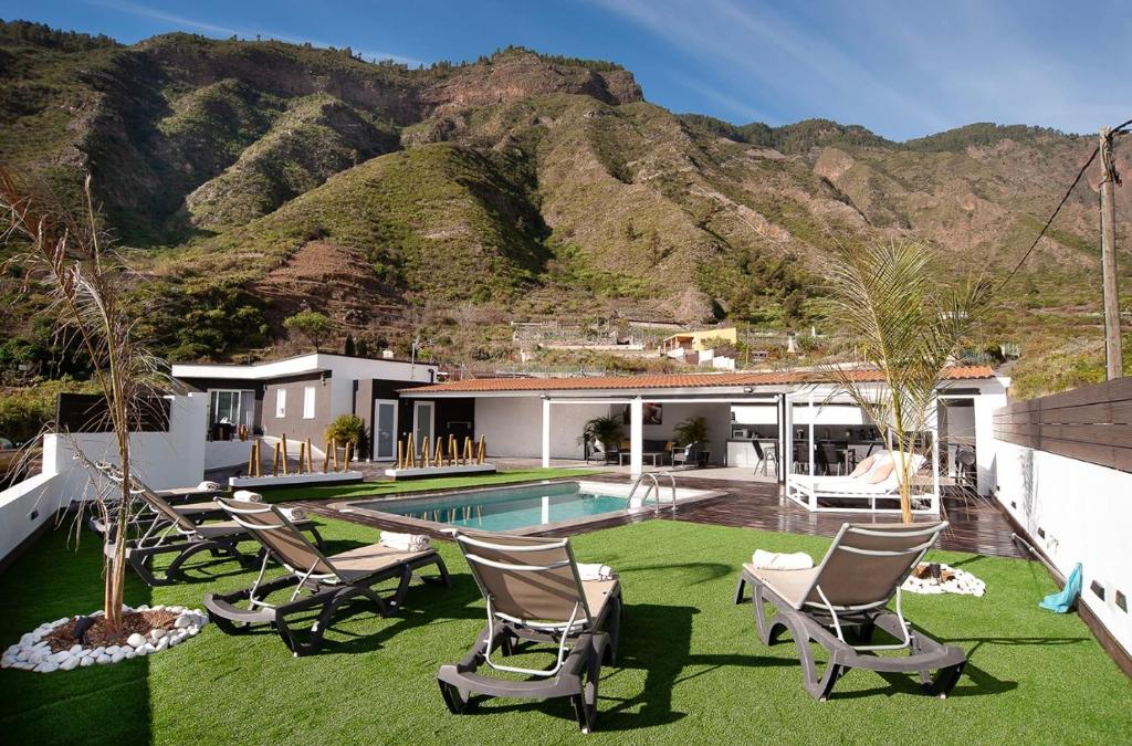 a yard with chairs and a swimming pool with a mountain at Villa Nahuel in Santa Cruz de Tenerife