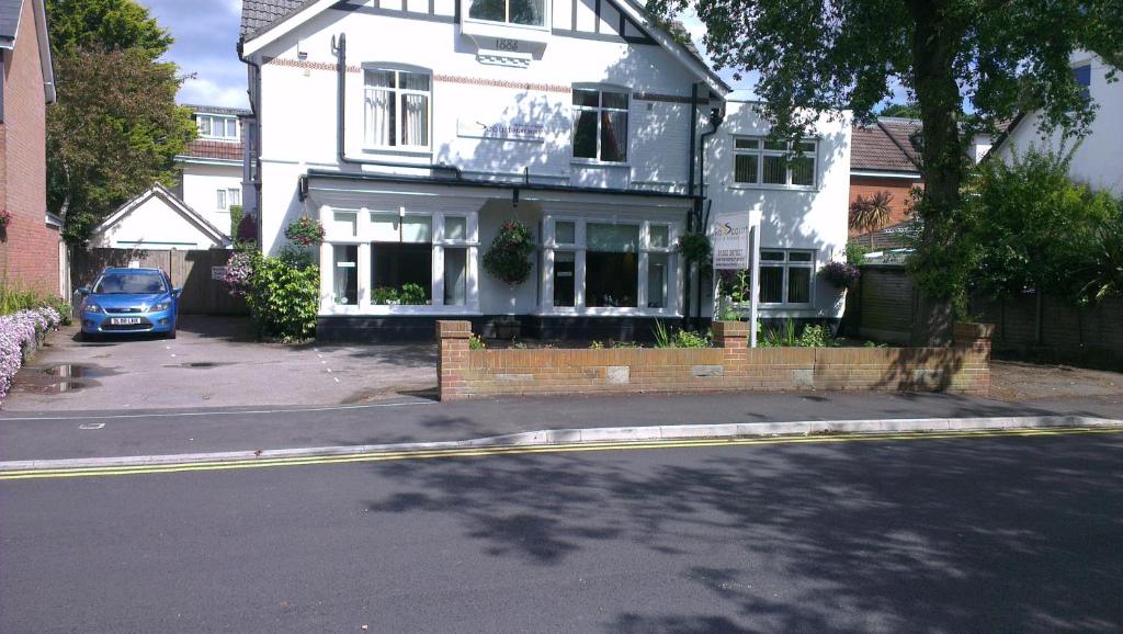 伯恩茅斯的住宿－羅斯科爾特成人酒店，前面有一辆蓝色汽车停放的白色房子