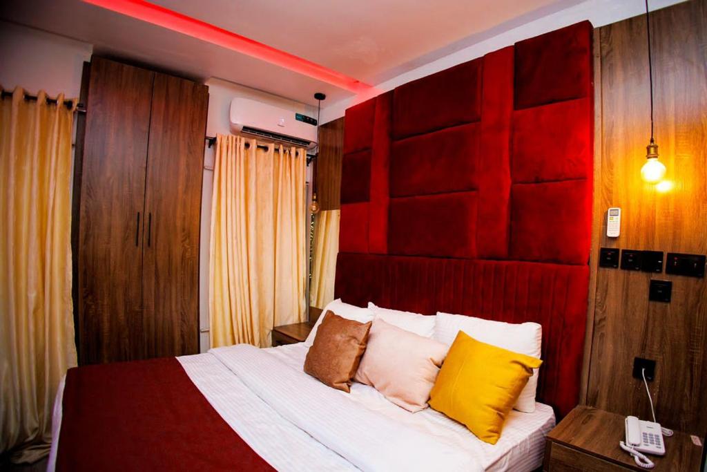 a bedroom with a bed with red and yellow pillows at Vic & J Lounge and Hotel Asaba in Asaba