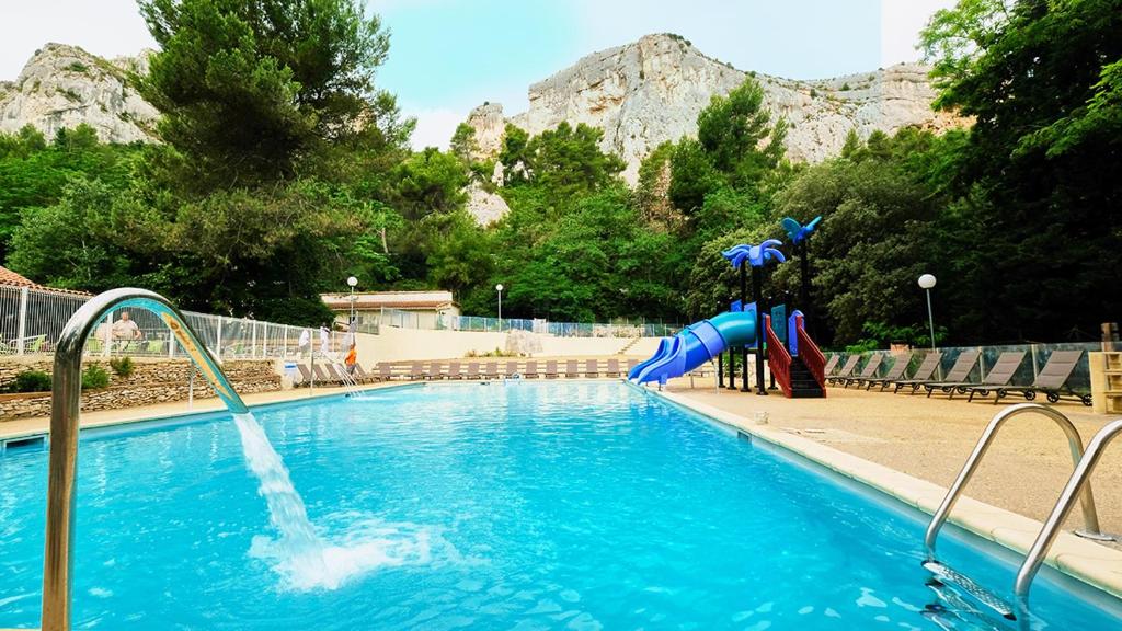 une piscine avec un toboggan aquatique face à une montagne dans l'établissement Camping maeva Respire La Vallée Heureuse, à Orgon 26 autres photos