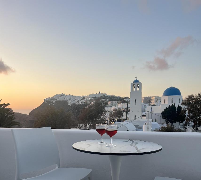 dos copas de vino sentadas en una mesa en un balcón en Villa Fotini en Firostefani