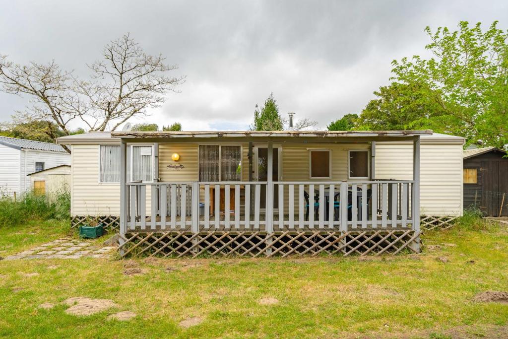 une petite maison jaune avec une clôture blanche dans l'établissement Mobilhome Mh287 La Tremblade, à La Tremblade