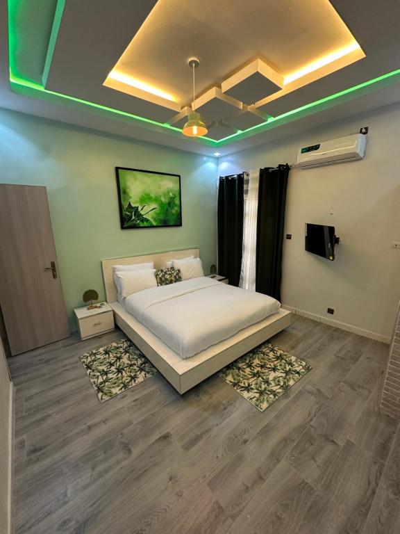 Resid’homes Appart’hotel Saint-Louis في سانت-لويس: غرفة نوم بسرير في غرفة ذات اضاءة خضراء