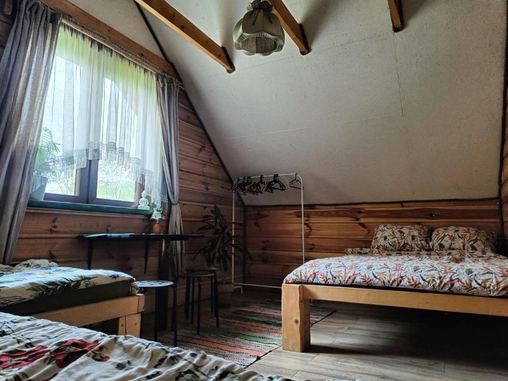 een zolderkamer met 2 bedden en een raam bij Domek w Łupkowie in Komańcza