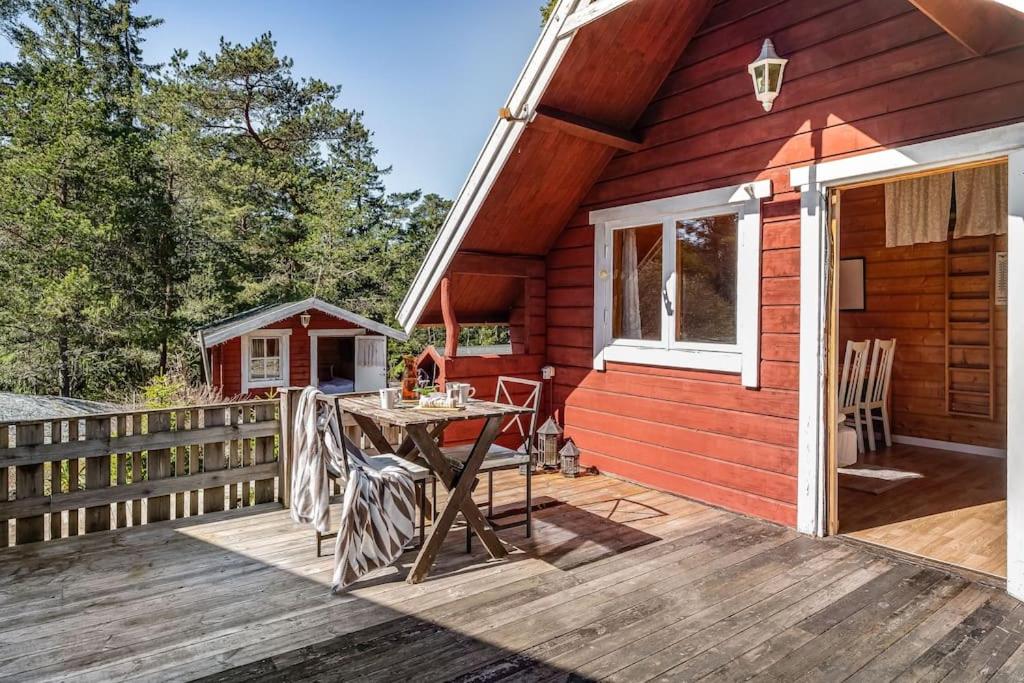 um camarote vermelho com uma mesa num deque de madeira em Cosy Cottages Close To Water em Djurhamn