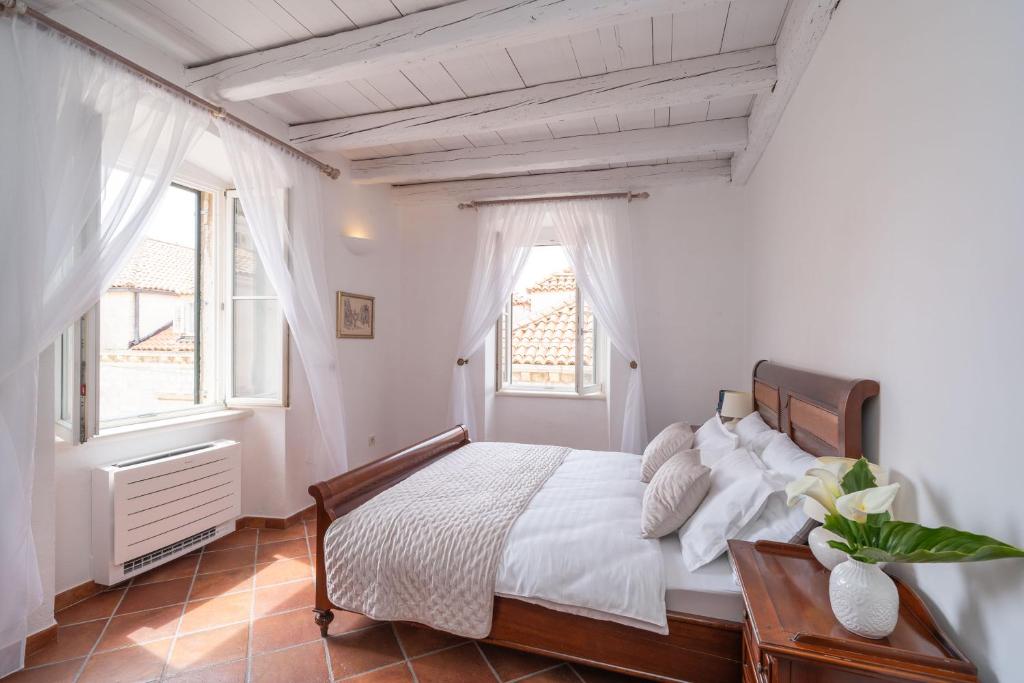 ein weißes Schlafzimmer mit einem großen Bett und Fenstern in der Unterkunft FORTUNATA Apartment in Dubrovnik