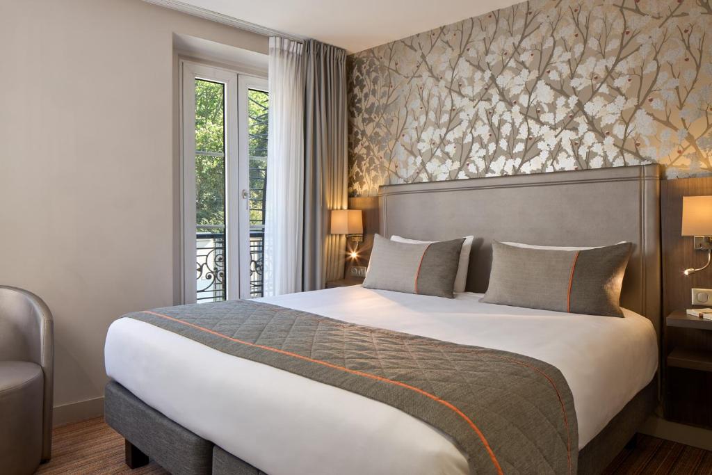 パリにあるティムホテル ガル ドゥ レスト（旧 ア ラ ヴィラ サン マルタン）の大きなベッドと窓が備わるホテルルームです。