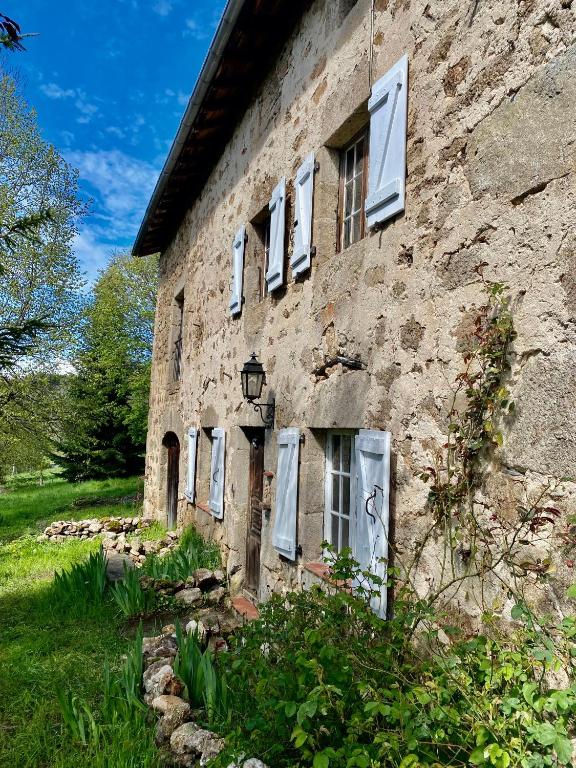 un vieux bâtiment en pierre avec des fenêtres blanches et de l'herbe dans l'établissement Le 1830, à Églisolles