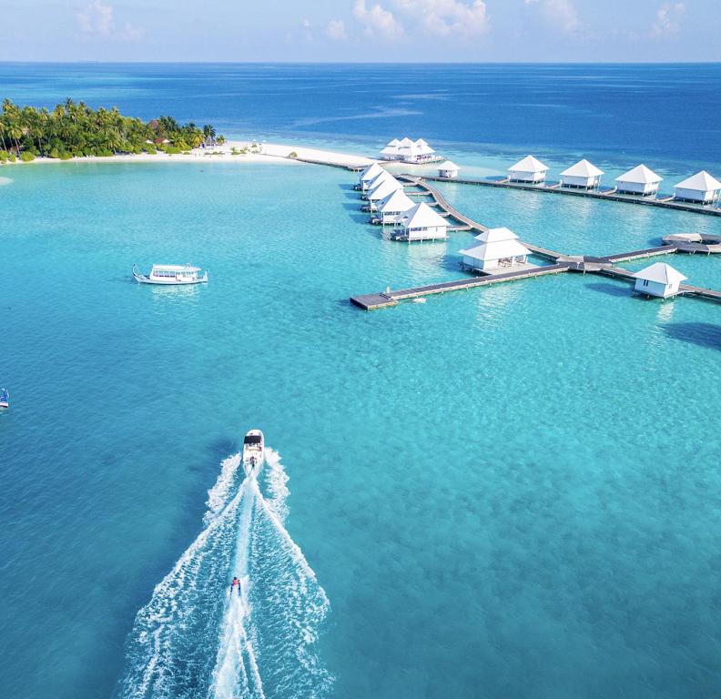 an island in the ocean with a boat in the water at Diamonds Athuruga Maldives Resort & Spa in Athuruga Island