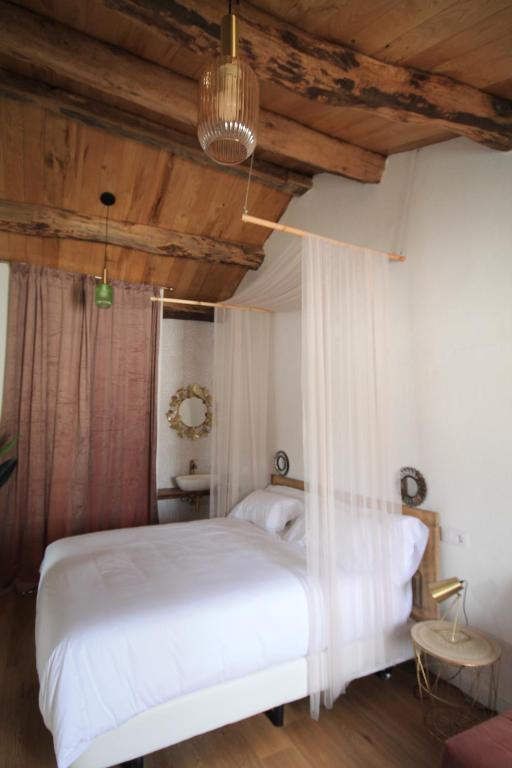 a bedroom with a white bed and wooden ceilings at HOTEL CASAS DA FORTALEZA Casa do Garda in Outeiro de Rei