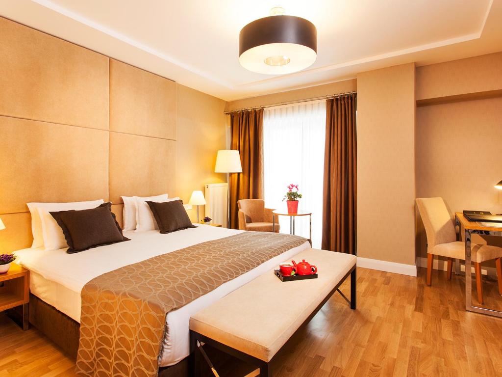 イスタンブールにあるNidya Hotel Esenyurtの大きなベッドとテーブルが備わるホテルルームです。