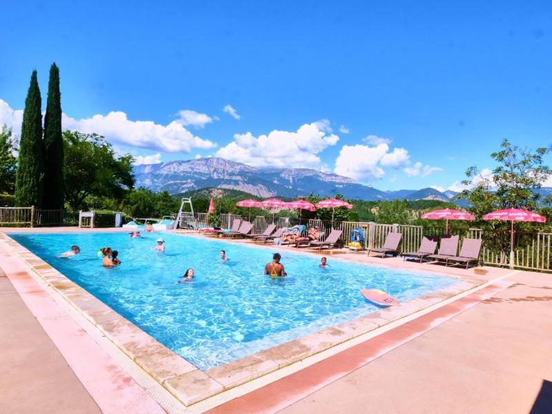 - un groupe de personnes dans une piscine avec parasols dans l'établissement Camping maeva Escapades Le Couriou, à Recoubeau-Jansac