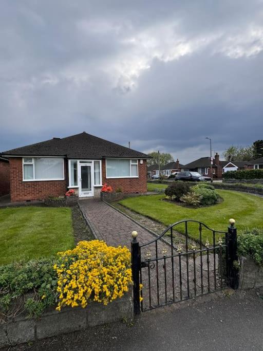 a house with a gate and yellow flowers in the yard at 230 Councillor Lane in Cheadle