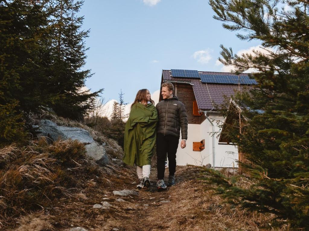 Un uomo e una donna in piedi su un sentiero di fronte a una casa di Jambrichova chata a Vysoké Tatry