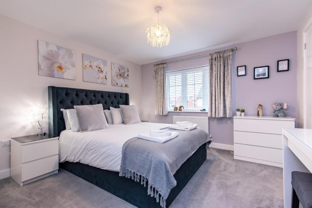 - une chambre avec un grand lit et un lustre dans l'établissement 4 Bedroom Detached House Ideal for Families and Corporate Stays in Radcliffe on Trent, à Burton Joyce