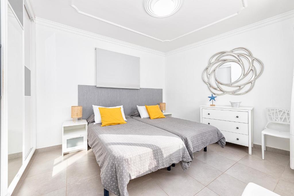 um quarto branco com uma cama com almofadas amarelas em Apartamento con vistas al mar em Arinaga
