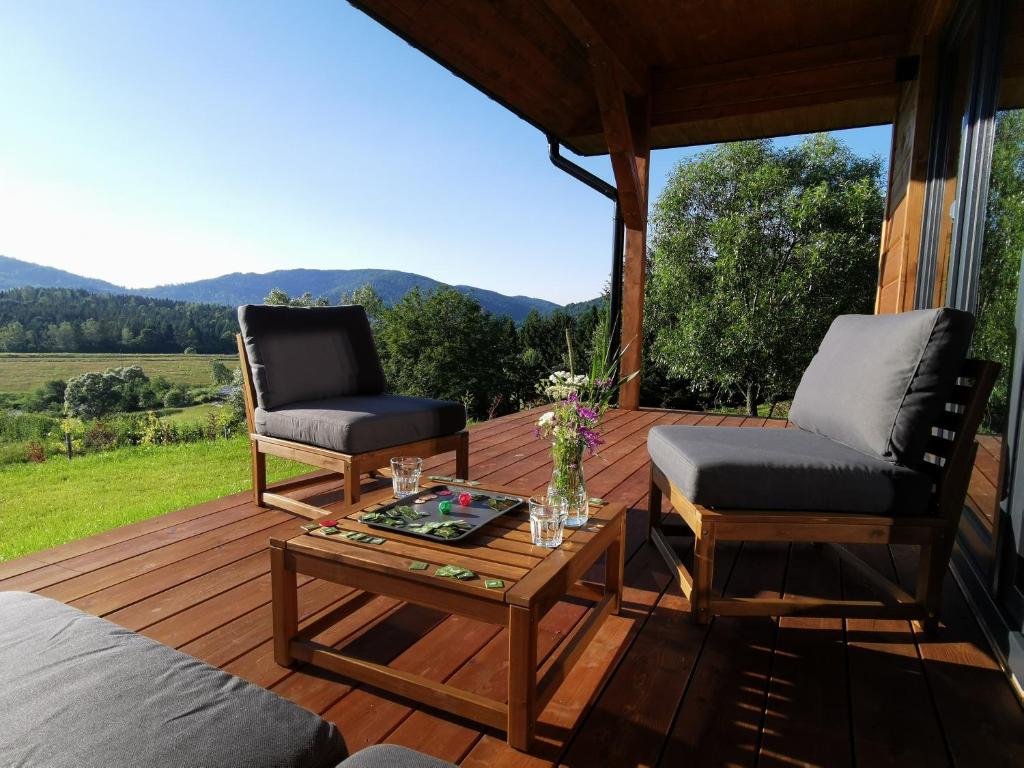 una terraza de madera con 2 sillas y mesa de centro en Na Skraju Nieba en Smerek