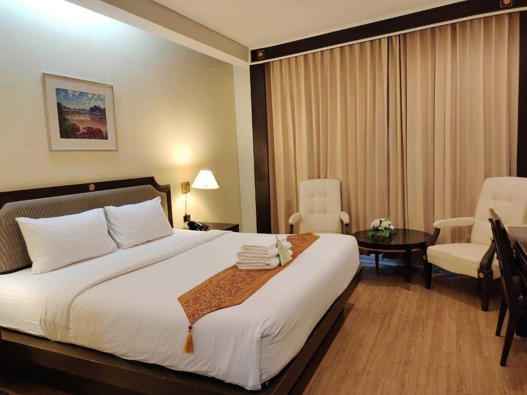 a hotel room with a bed and a table and chairs at Wangchan Riverview in Phitsanulok