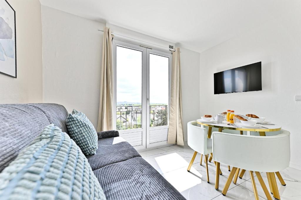 sala de estar con sofá, mesa y ventana en Appartement proche de Paris - Gagny, en Gagny