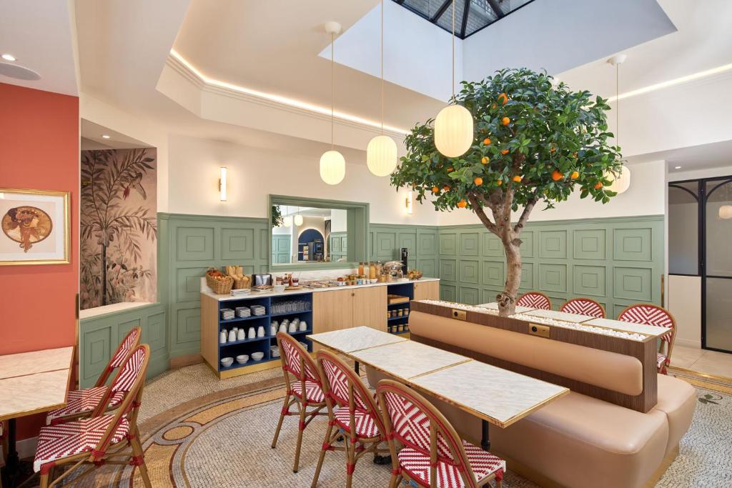 un restaurant avec une table, des chaises et un arbre dans l'établissement Timhotel Palais Royal, à Paris