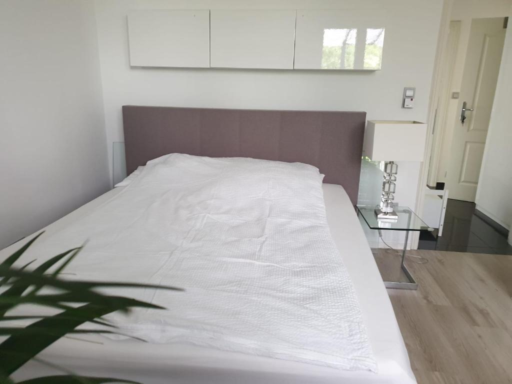 ein weißes Bett in einem Zimmer mit einem Tisch in der Unterkunft Apartment im Grünen zwischen Messe & Flughafen Köln! in Köln