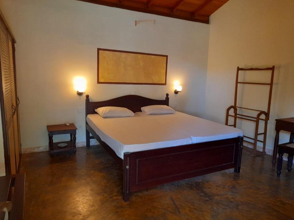 貝魯沃勒的住宿－Seetharama Garden of Life，一间卧室配有一张带两盏灯和两张桌子的床。