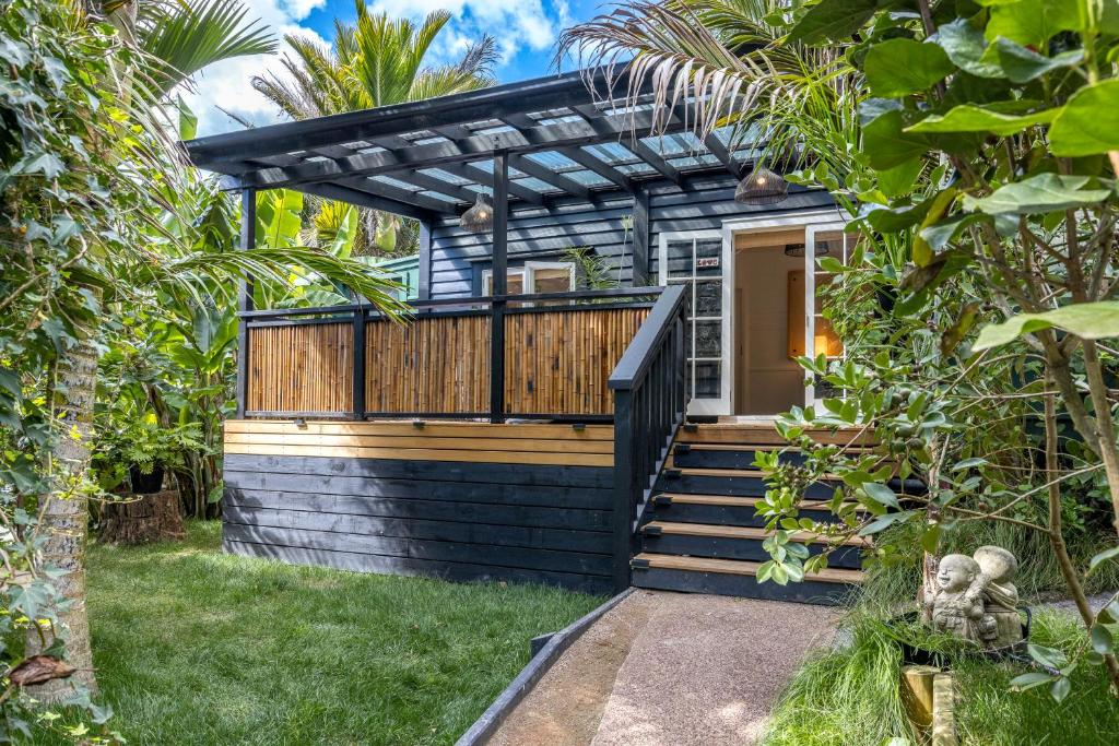 a house with a deck with a pergola at Jungle Cottage Escape in Auckland