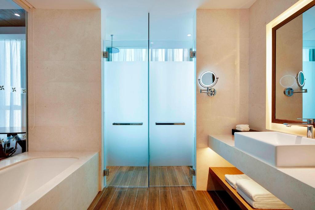 a bathroom with a shower and a tub and a sink at Four Points by Sheraton Changchun Hi-Tech Zone in Changchun