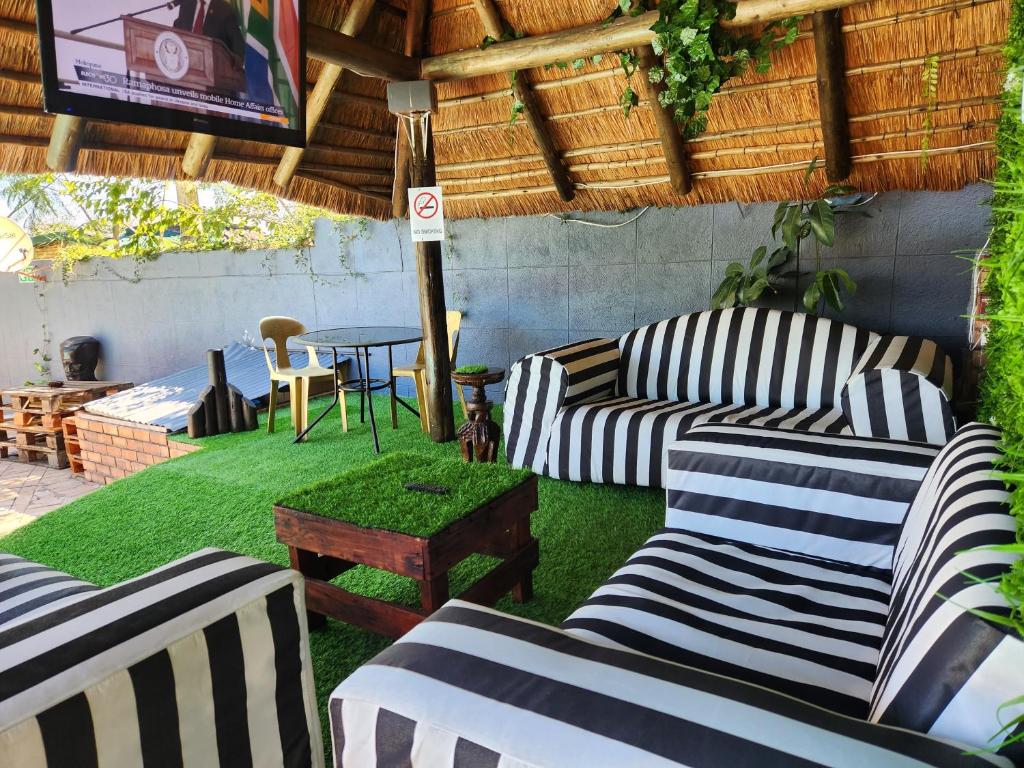 a patio with striped couches and a table with a tv at Casa Palmeira in Nelspruit