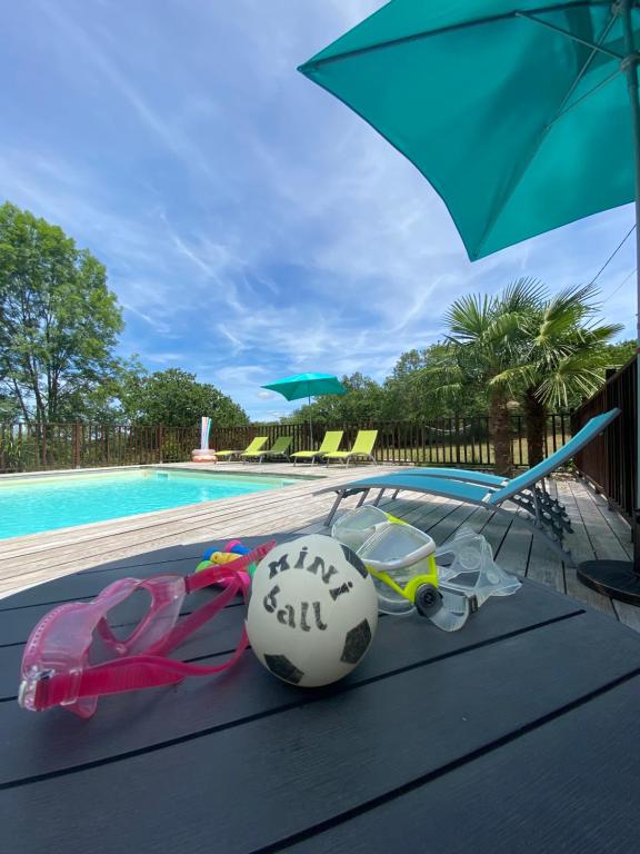 un ballon de football posé sur une table à côté d'une piscine dans l'établissement Chalet les chênes verts - Périgord proche grottes de Lascaux, à Saint-Amand-de-Coly