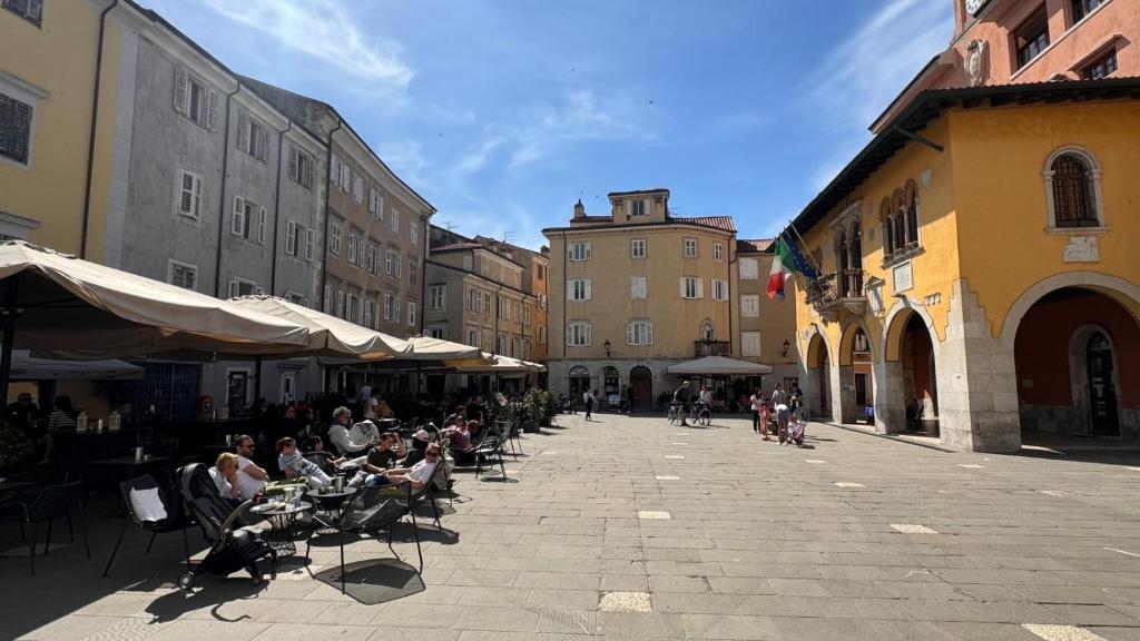 Un groupe de personnes assises à des tables dans une rue dans l'établissement Casa di Giovanni - Italien, à Muggia