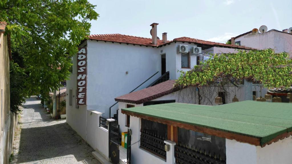 a white building with a green roof on a street at Ados Hotel in Cesme