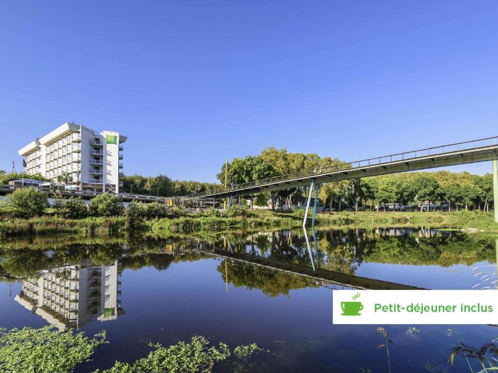 a bridge over a body of water with a building at ibis styles Dax Centre in Dax
