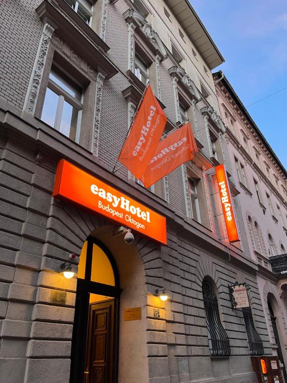 un edificio con letreros naranjas en la parte delantera. en easyHotel Budapest Oktogon, en Budapest