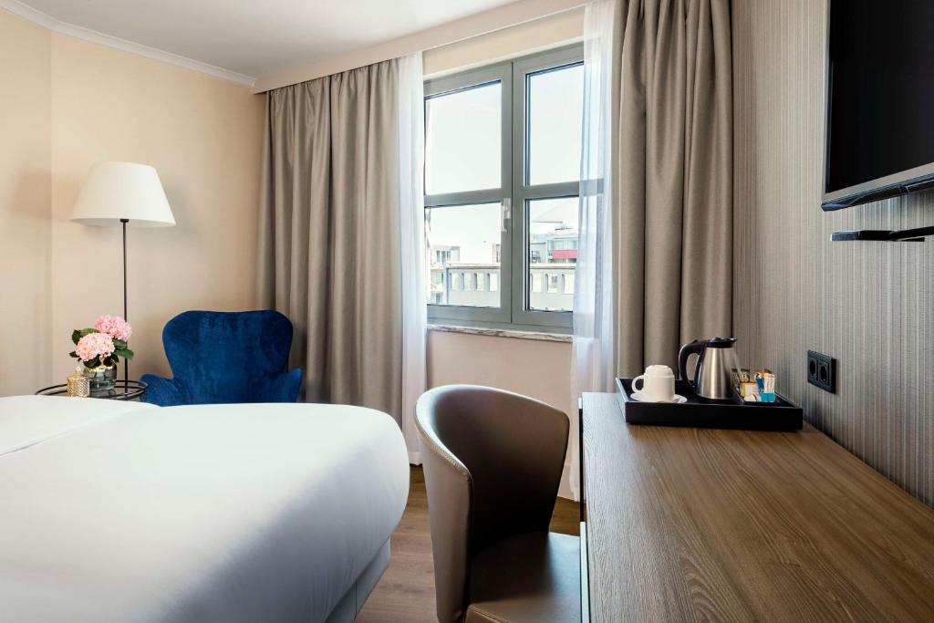 ベルリンにあるNH ベルリン クアフュルステンダムのベッドと窓が備わるホテルルーム