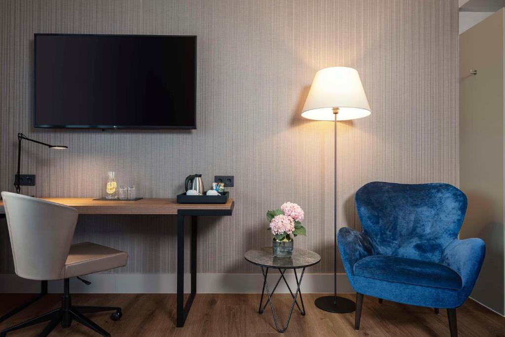 a room with a desk and a blue chair and a lamp at NH Berlin Kurfürstendamm in Berlin