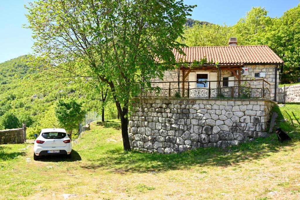 ein weißes Auto, das vor einer Steinmauer parkt in der Unterkunft Martina in Cetinje
