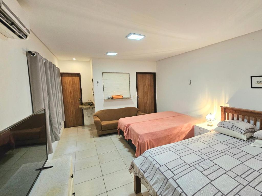 um quarto de hotel com duas camas e um sofá em Flor de Lótus Suites em Tamandaré