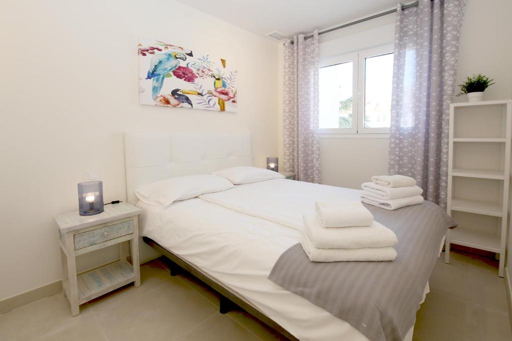biała sypialnia z łóżkiem i oknem w obiekcie Apartment BEATRIX w mieście Estepona