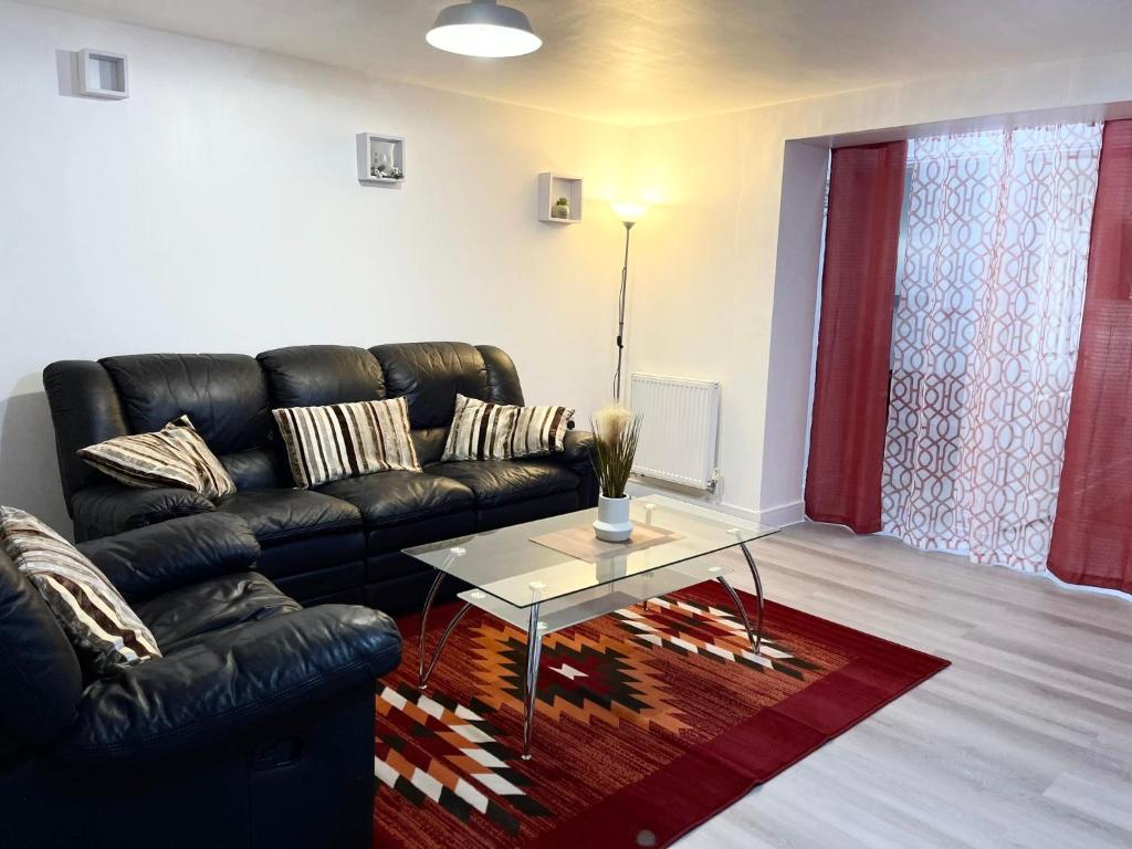 sala de estar con sofá de cuero negro y mesa en Crescent Apartment - Two bedroom en Goodmayes