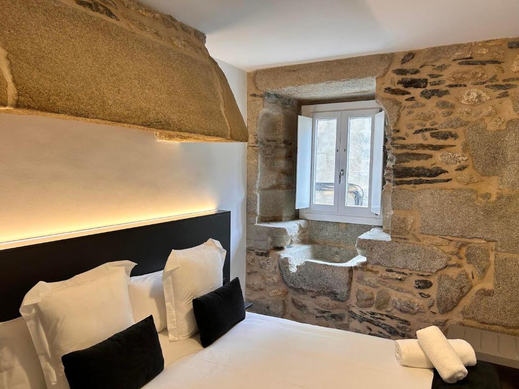 a bedroom with a bed with a stone wall at APARTAMENTOS NADA Ó NORTE Centro in Viveiro