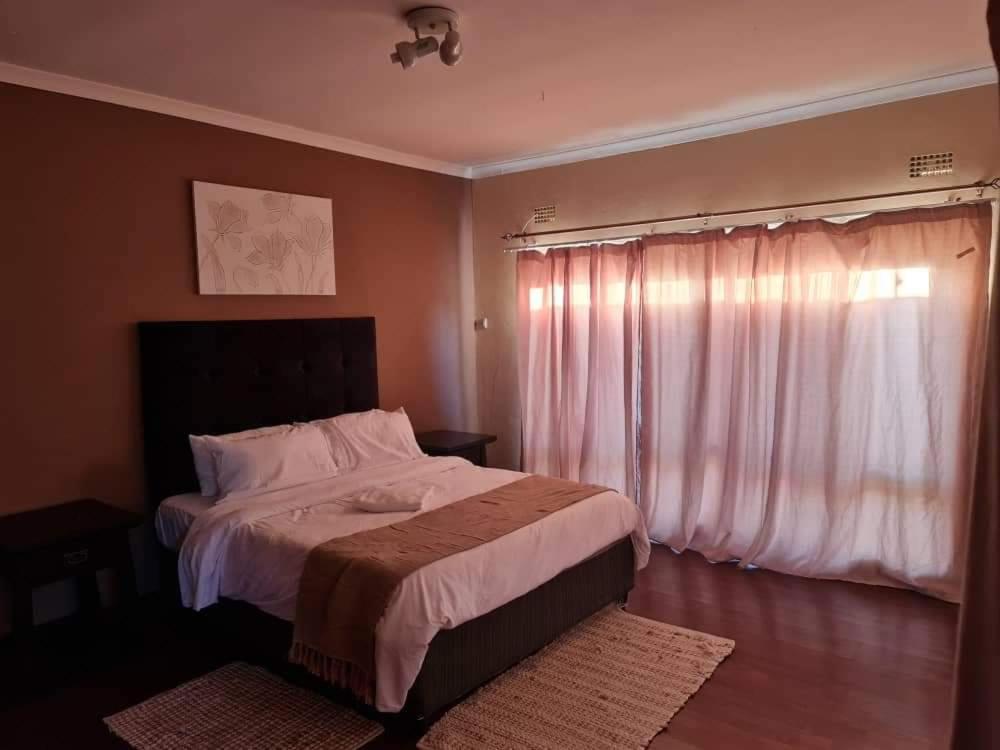 a bedroom with a large bed and a window at Lake road Apartment in Lusaka