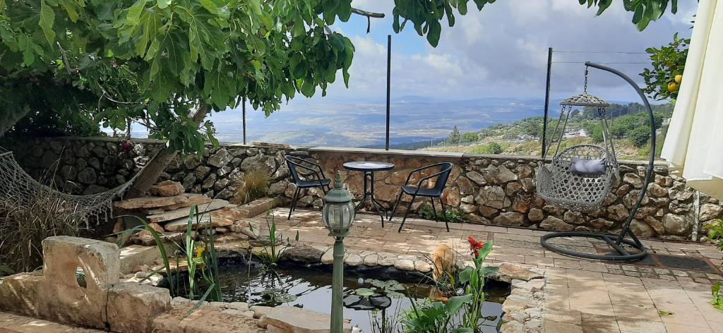 a patio with a pond and a table and chairs at Self-Contained Garden apartment with Galilee sea & mountains view 2 in Safed