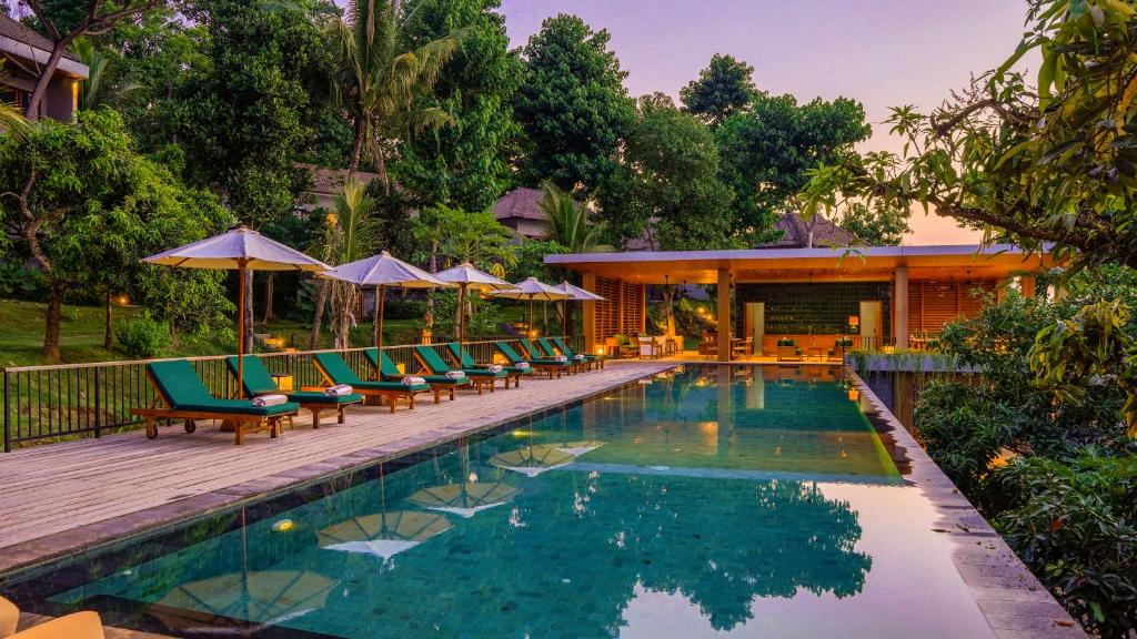 einen Pool mit Stühlen und Sonnenschirmen neben einem Resort in der Unterkunft Sanglung Villas & Suites in Kubutambahan