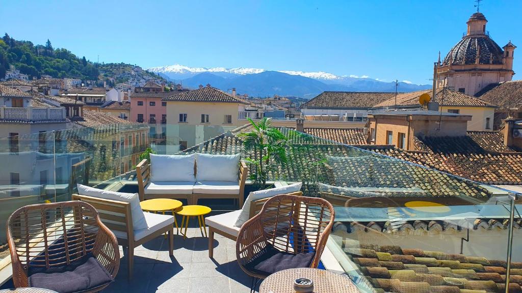a balcony with chairs and tables and a view of a city at Casual Ilbira Granada in Granada