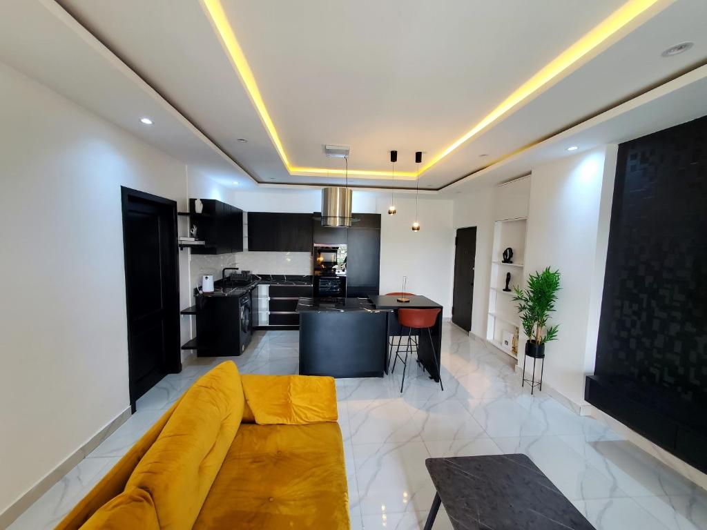 un salon avec un canapé jaune et une cuisine dans l'établissement Star tower, à Accra