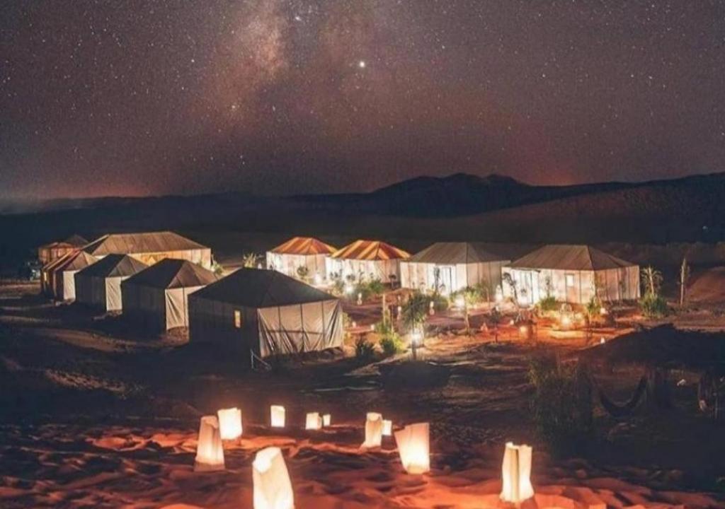 um grupo de tendas num campo à noite em Fantastic Luxury Camp em Merzouga